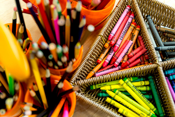 Crayons in a basket and colored pencils in a cup