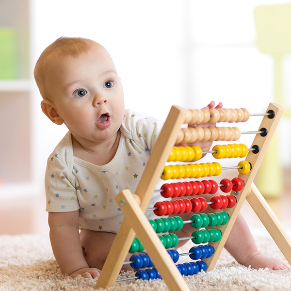 Little boy playing with classic wooden educational counting toy with beads
